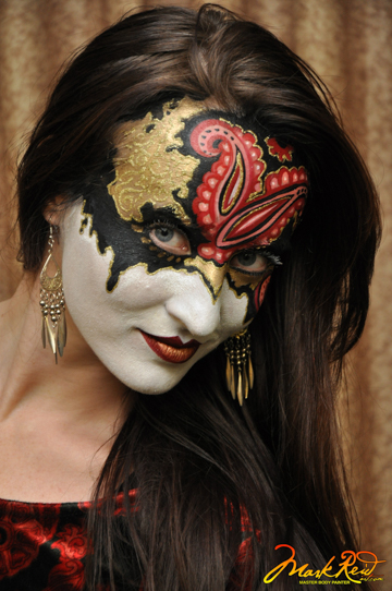 brunette woman in a red and gold mask with black frames that appear to drip down her face onto a white lower half of the face